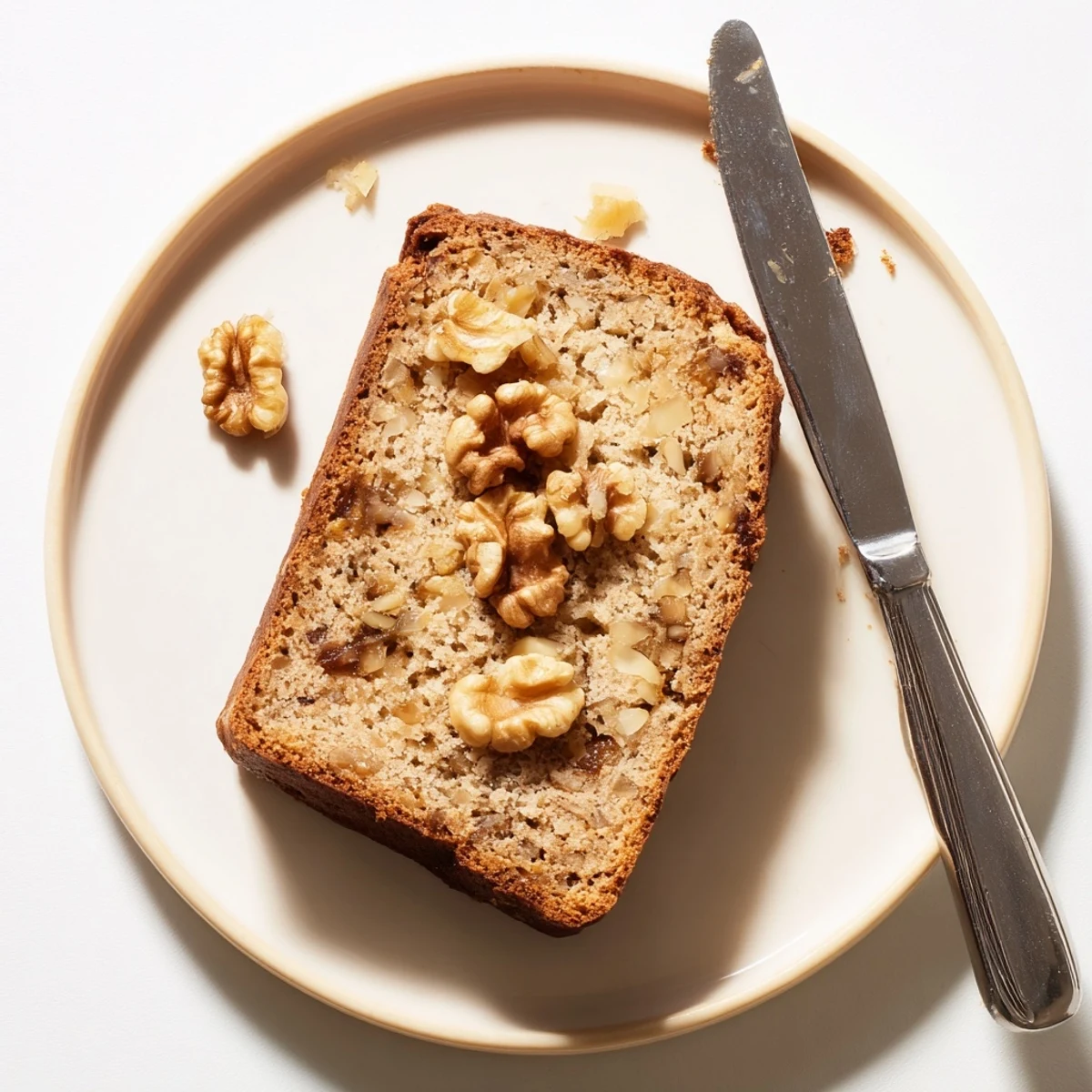 Warm slice of banana nut bread drizzled with butter beside a steaming mug