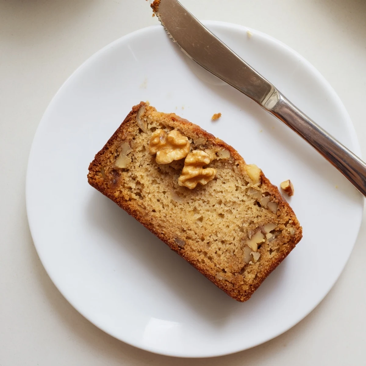 Moist banana nut bread topped with crunchy pecans on a cozy linen napkin