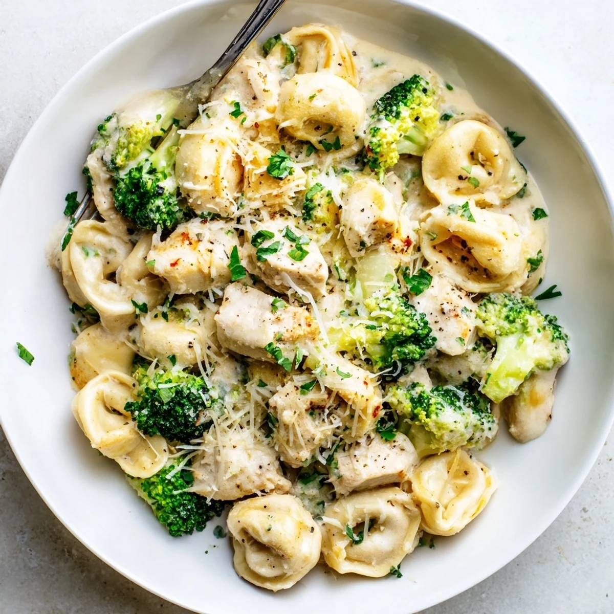 Plate of Creamy Garlic Parmesan Tortellini Chicken Broccoli Recipe, garnished with parsley  