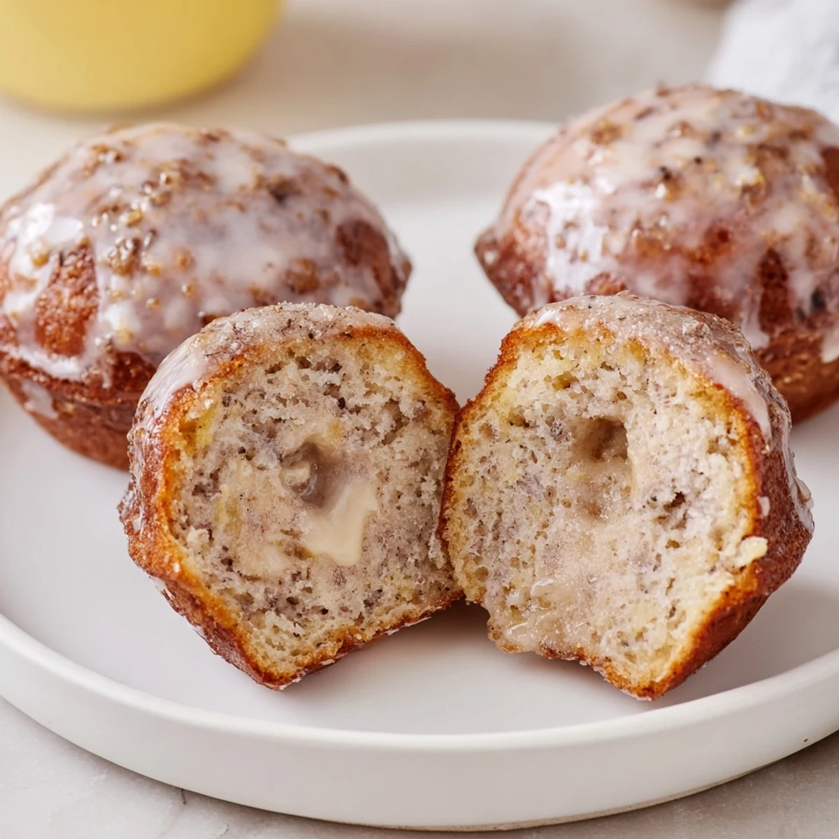Glazed Banana Donuts piled on a plate, sweet vanilla scent wafting