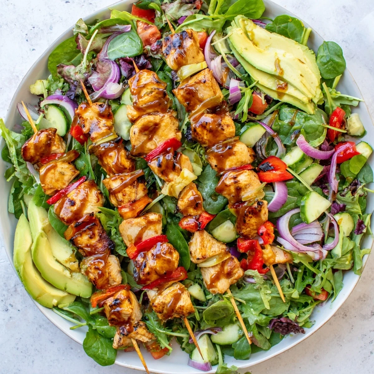 Summer BBQ chicken skewer salad featuring crisp greens, juicy tomatoes, creamy avocado, and smoky grilled chicken