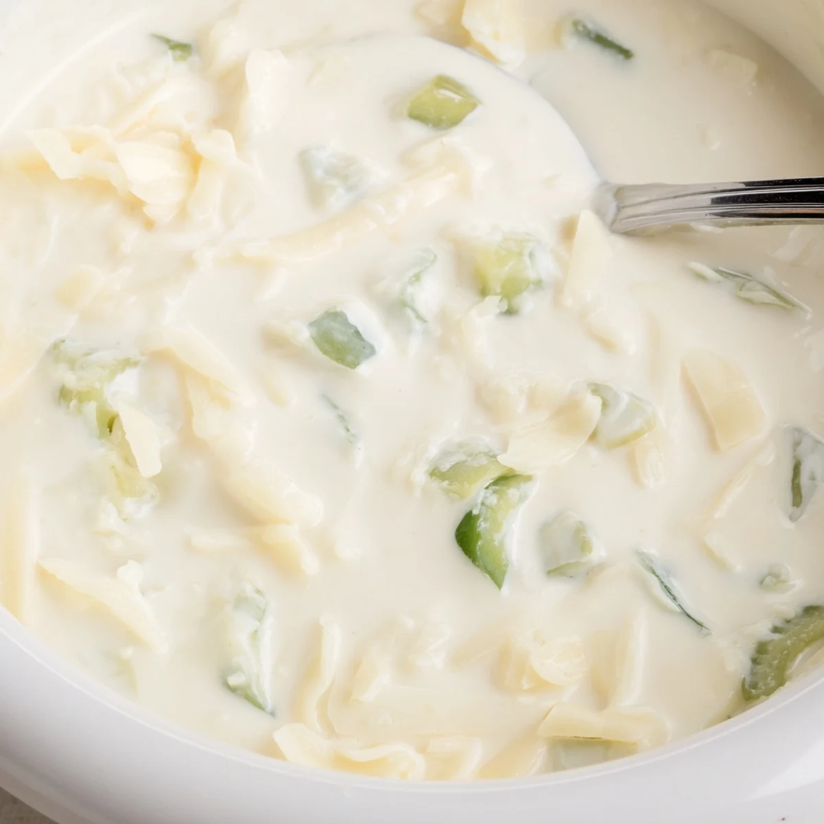 Creamy white queso dip served warm in a small cast iron skillet with garnish.