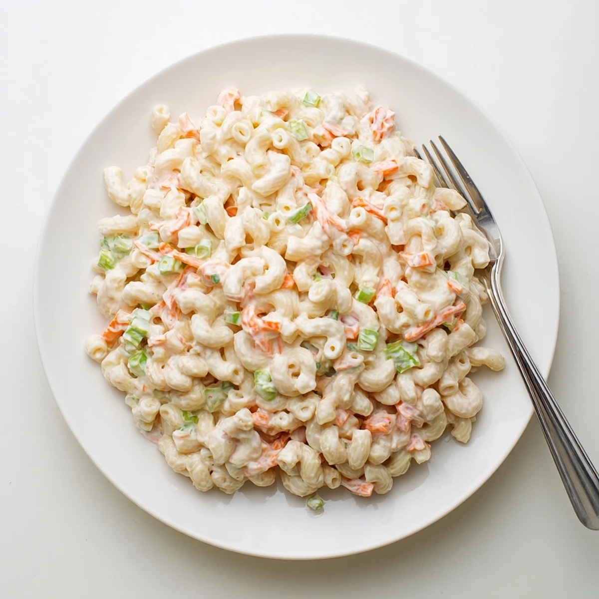 Scoop of Hawaiian style mac salad featuring finely chopped celery and onion in a tangy creamy dressing