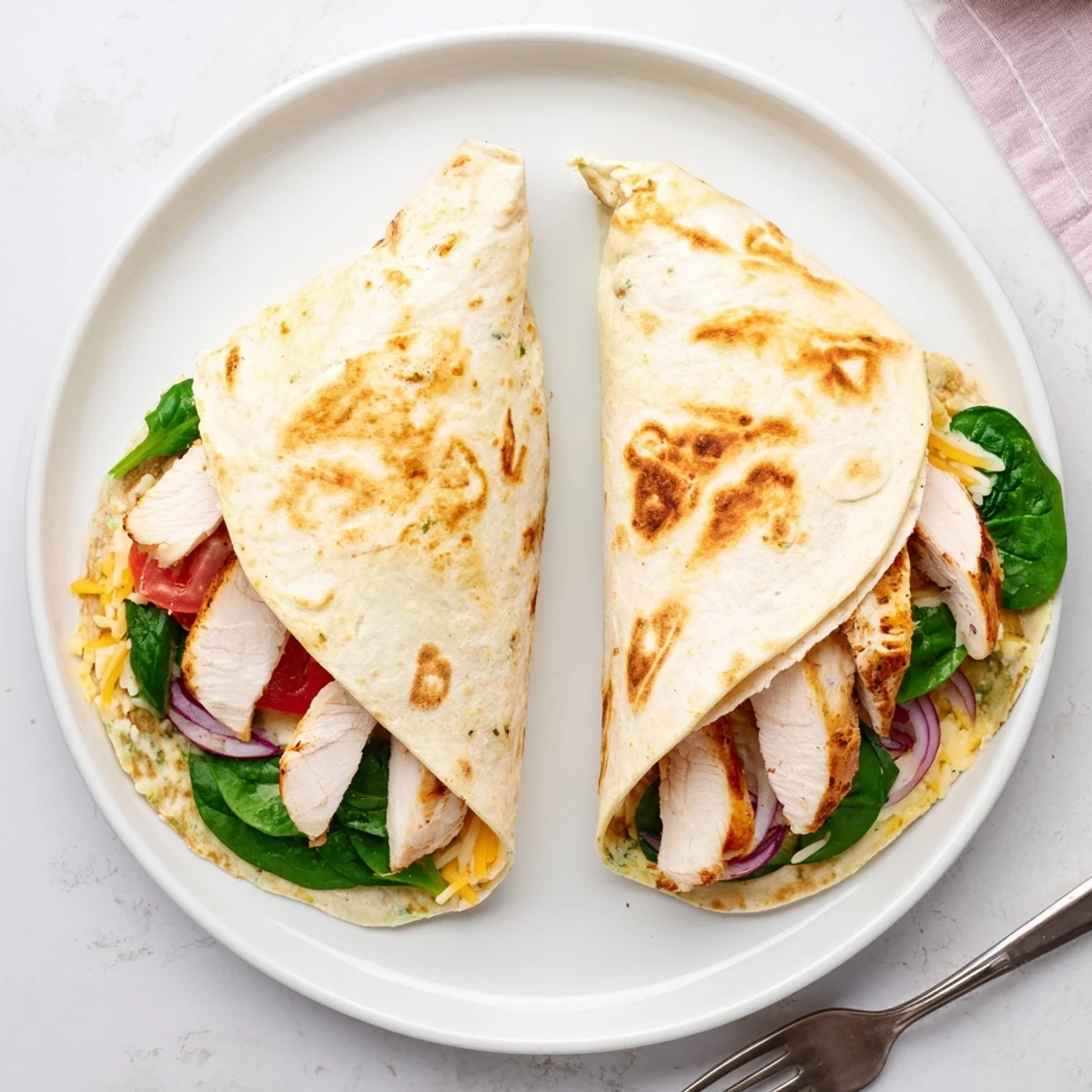 Warm Cheesy Garlic Chicken Wraps sliced in halves, steam rising, served with fries
