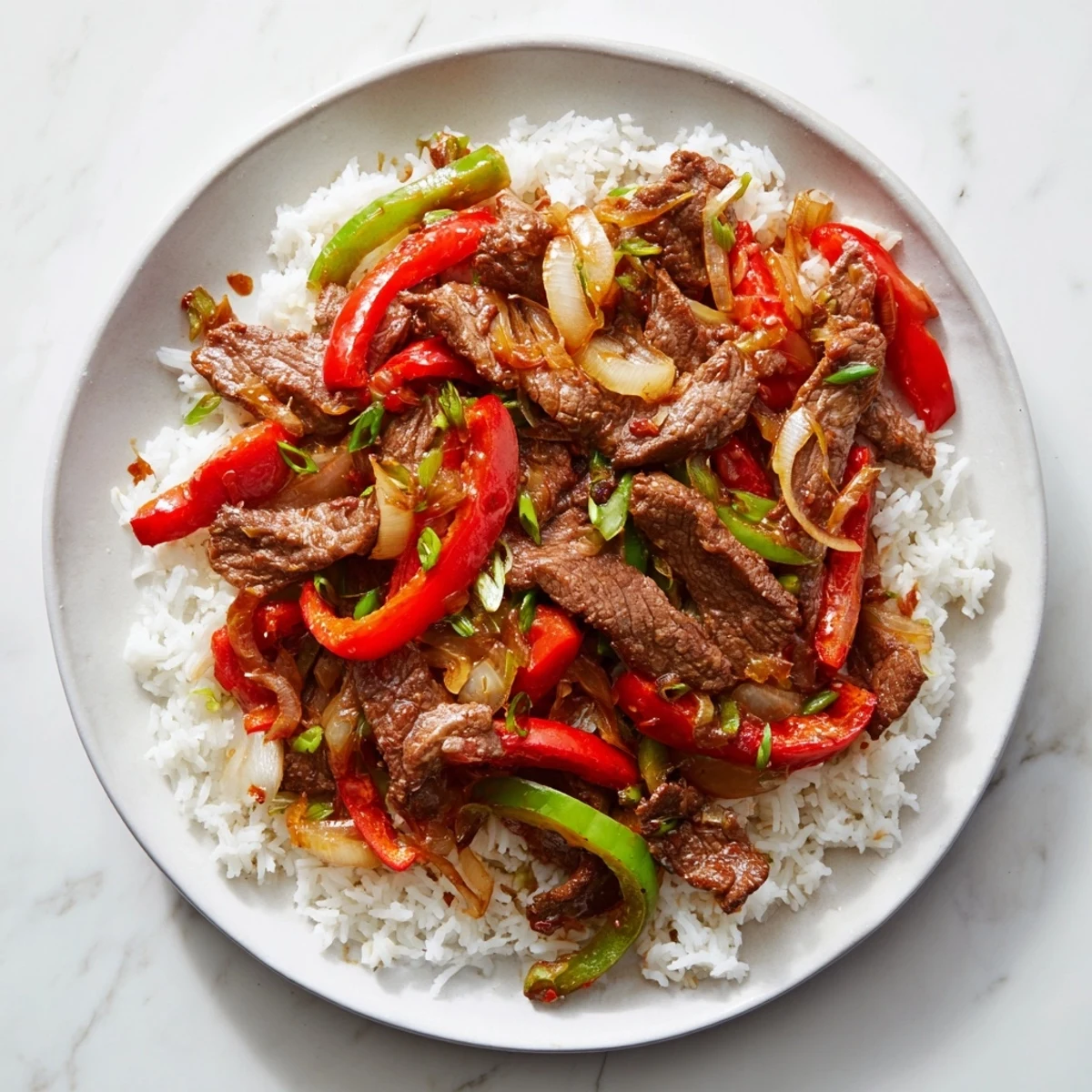 Sizzling spicy beef stir fry with chili garlic sauce tossed with colorful bell peppers over steaming white jasmine rice