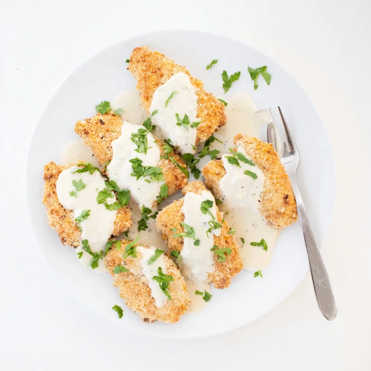 Savory breaded chicken cutlets topped with rich garlic creamy sauce garnished with fresh green parsley