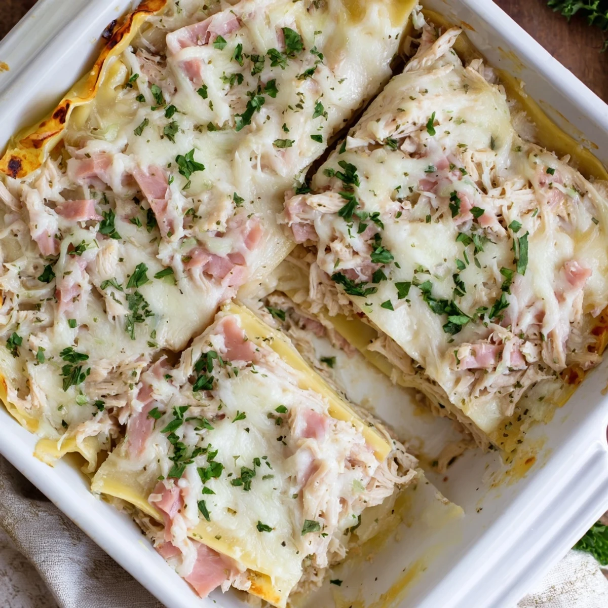 Baked Chicken Cordon Bleu Lasagna served in a rectangular dish featuring creamy white béchamel sauce