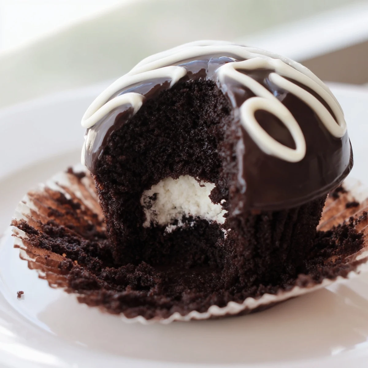 Moist Homemade Hostess Cupcakes topped with shiny glaze and signature white icing swirl