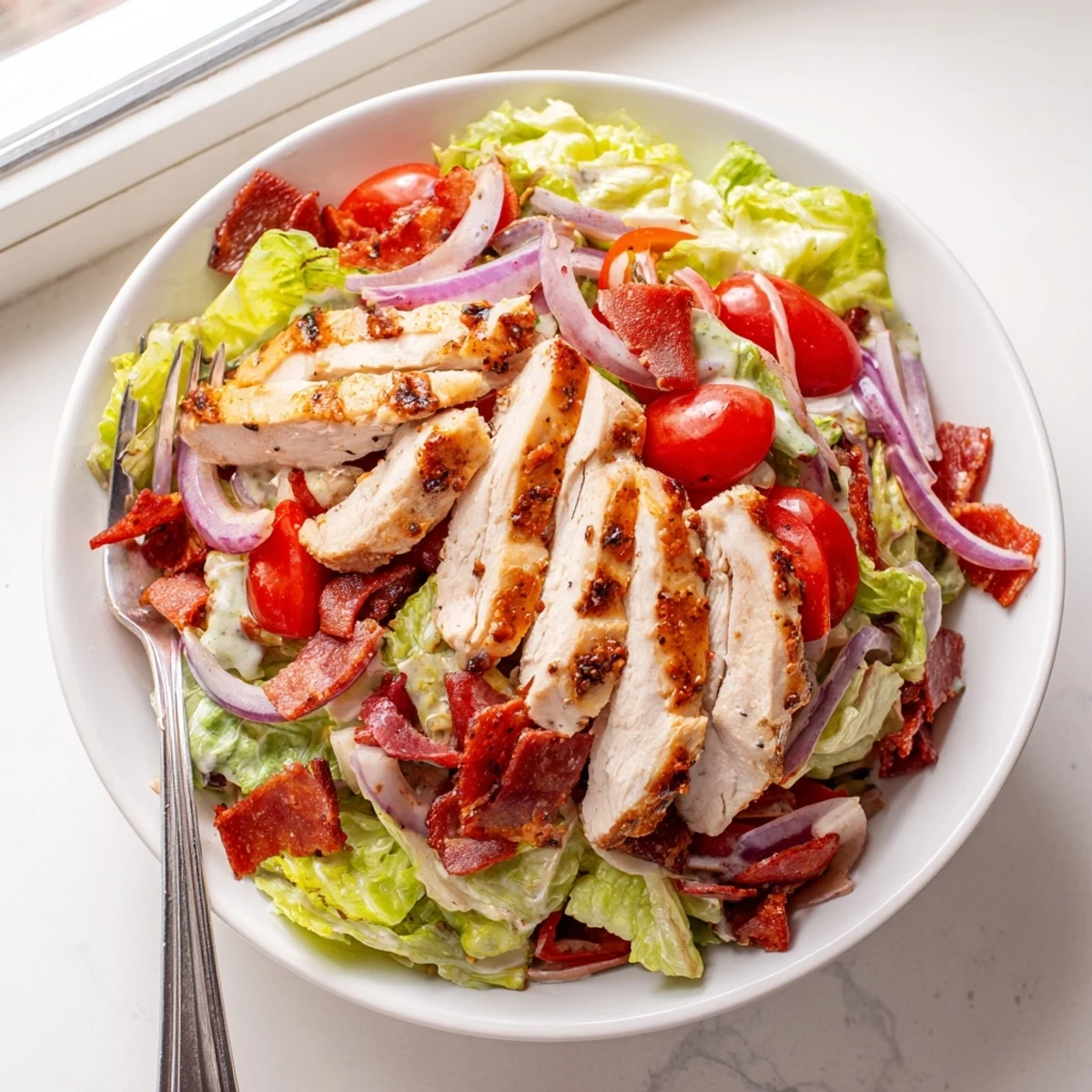 Hearty Italian Grinder Chicken Salad in a white bowl with red peppers and savory dressing.