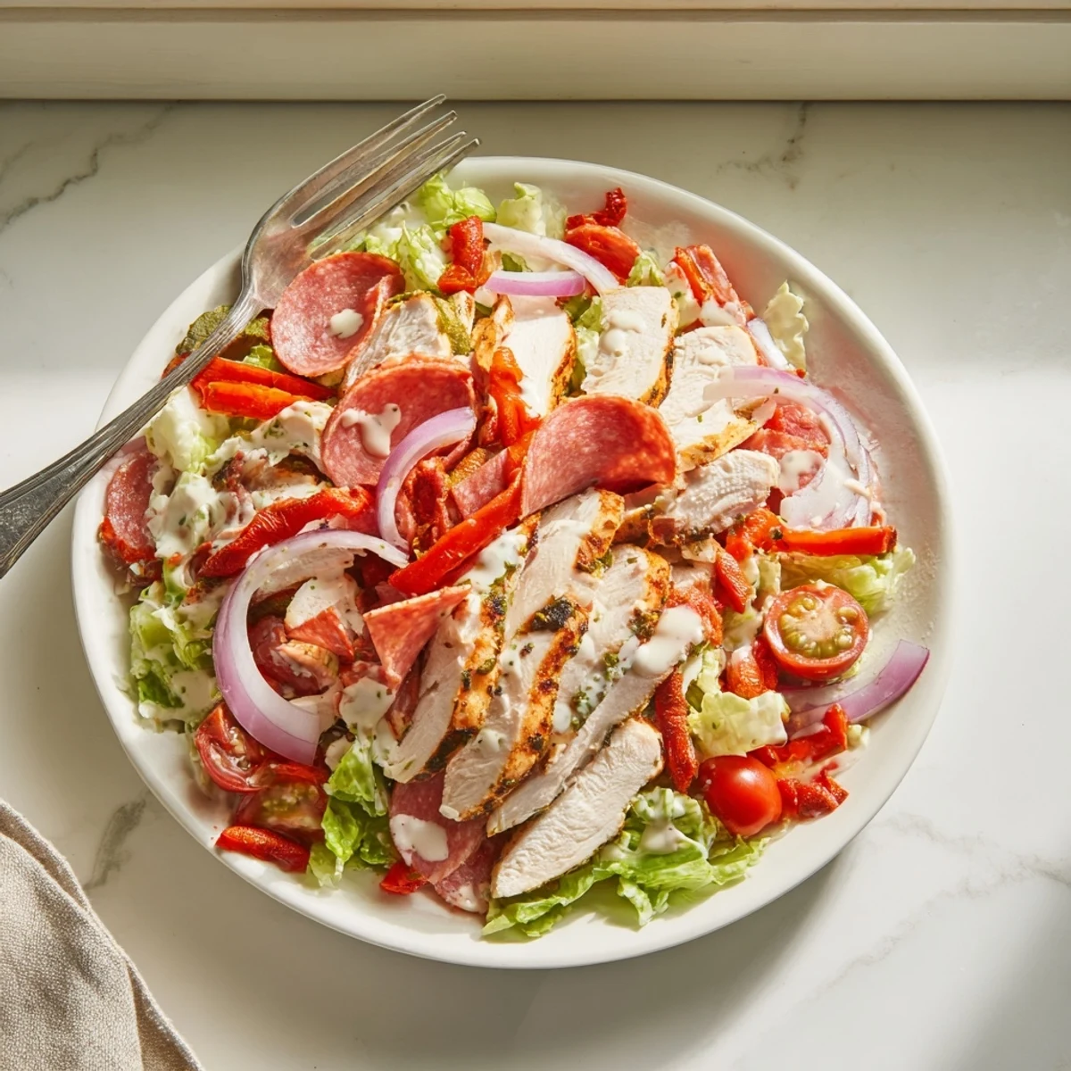 Close-up of zesty Italian Grinder Chicken Salad with lettuce, tomatoes, pepperoncini, and provolone.