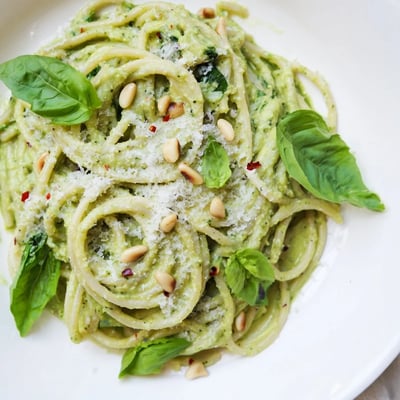 Freshly blended avocado and spinach sauce coats al dente spaghetti, ready to be served with a sprinkle of Parmesan and pine nuts.