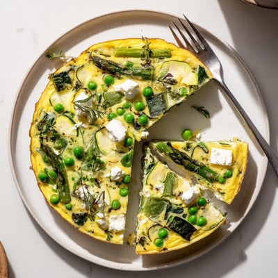 Sliced Spring Vegetable Frittata With Goat Cheese served with crusty bread.